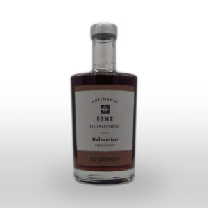 Eine Klarglasflasche mit der Aufschrift "Hoffmanns Essigmanufaktur Balsamico Lockstoff", gefüllt mit dunklem Balsamico-Essig, fotografiert auf weißem Hintergrund.